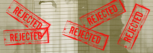 The word "REJECTED" stamped five times onto layers of lined paper.