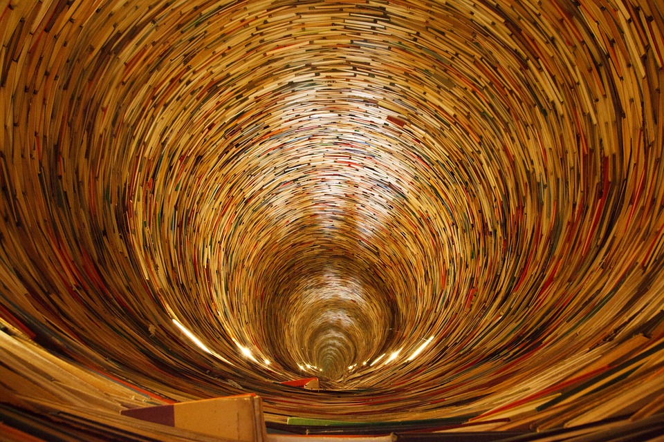Spirals of books in the shape of a tunnel.