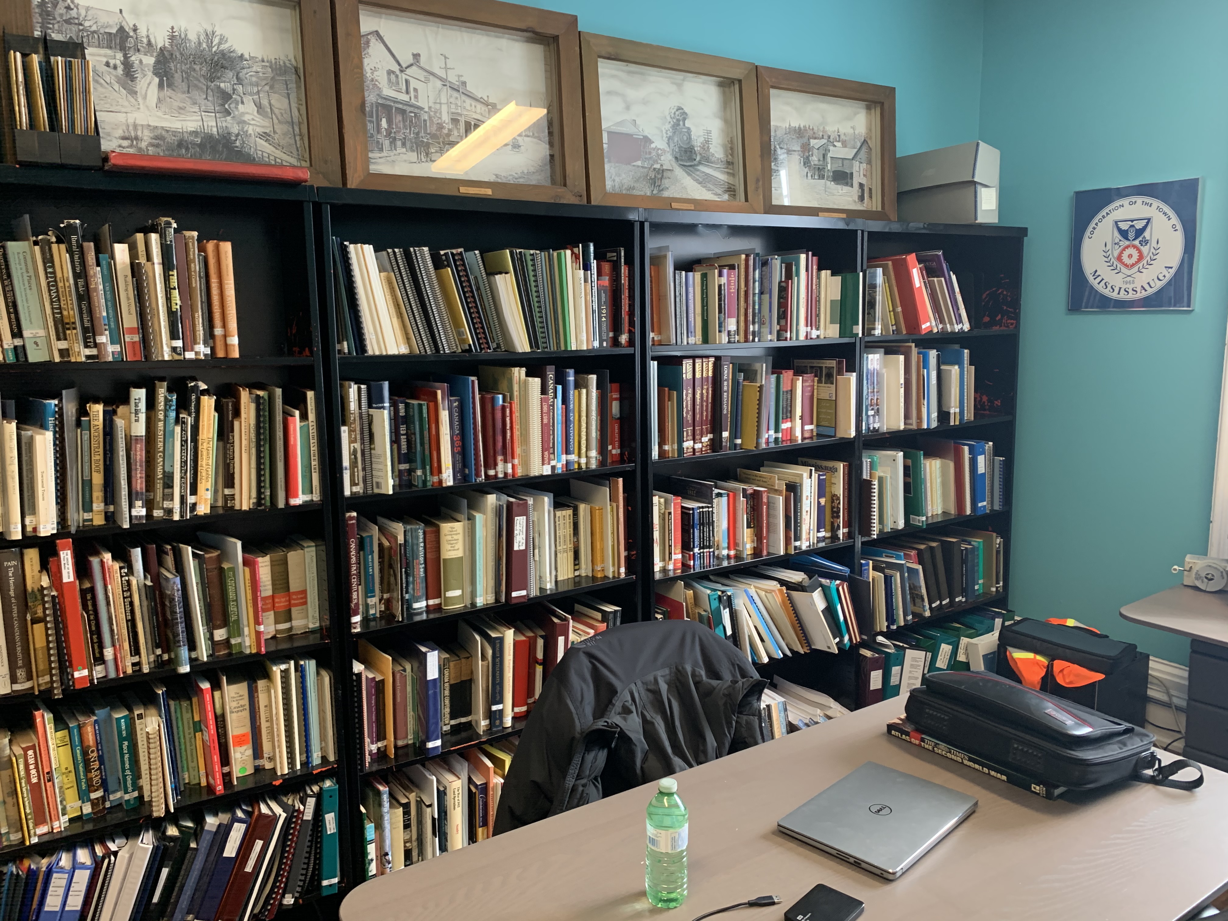 A bookshelf at the Heritage Mississauga office and a desk with my research and writing tools on it.