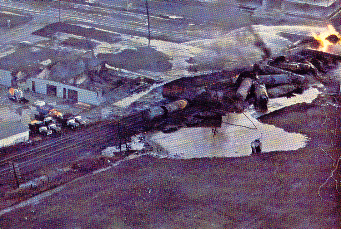 Image of the Train Derailment taken from above and the wrecked train and the fire are being quenched by remote hoses.