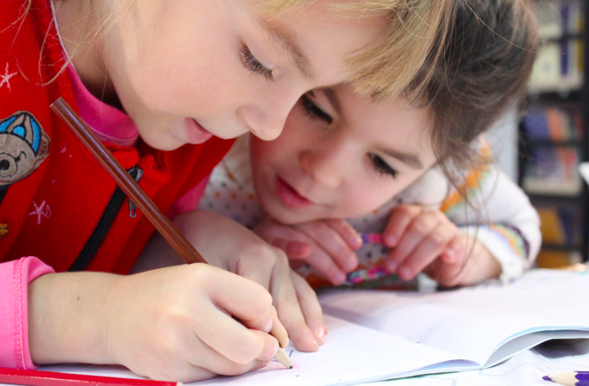 Two children writing in a notebook.